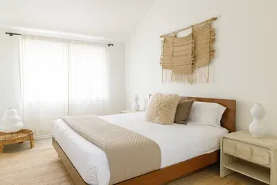 Bright, serene bedroom with soft natural light and warm neutral styling