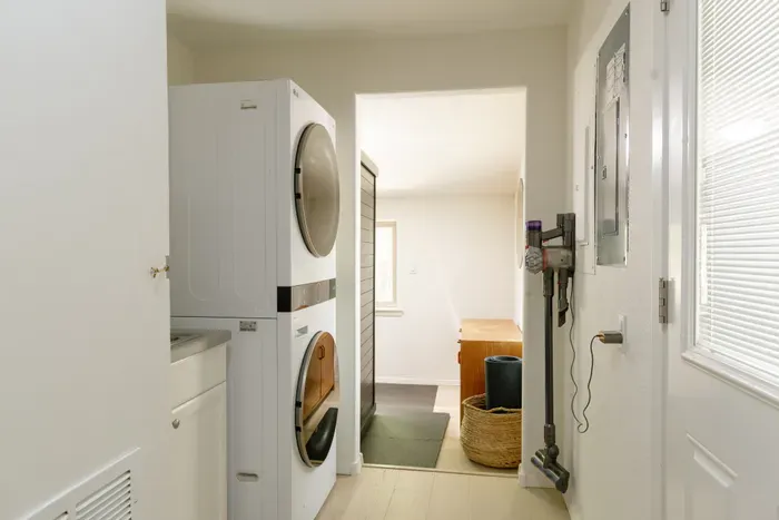 Bright in-home laundry area with stacked washer/dryer for added convenience