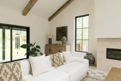 Bright designer living room with beams, fireplace, and garden views