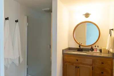 Bright modern bathroom with warm wood vanity and sleek frosted-glass shower