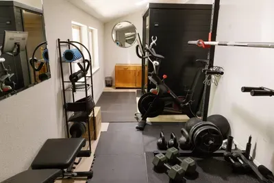 Private home gym with bike, weights, bench, and strength training setup