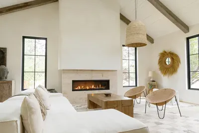 Bright vaulted living room with fireplace, beams, and designer seating