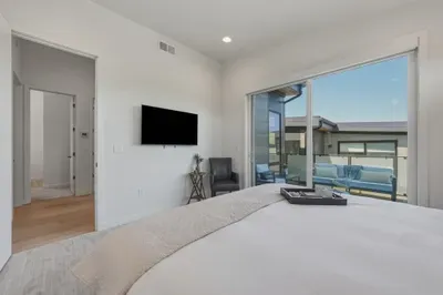 Bright modern bedroom with TV and private balcony seating