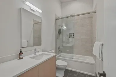Bright modern bathroom with sleek vanity and glass-enclosed tub-shower