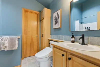 Bright blue bathroom with spacious vanity, modern fixtures, and warm wood accents