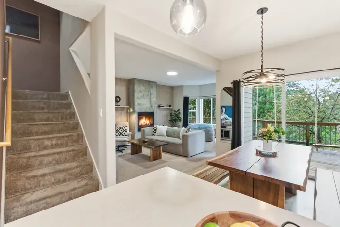 Bright open living space with fireplace, dining area, and scenic deck views