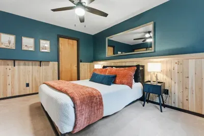 Cozy modern-rustic bedroom with queen bed, teal walls, and warm wood details