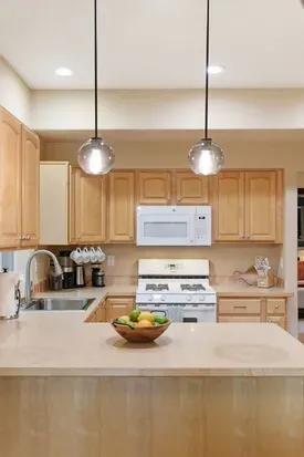 Bright kitchen with island seating, gas stove, and warm wood finishes