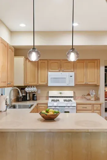 Bright kitchen with island seating, gas stove, and warm wood finishes