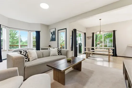 Bright open living space with large windows, cozy seating, and deck access