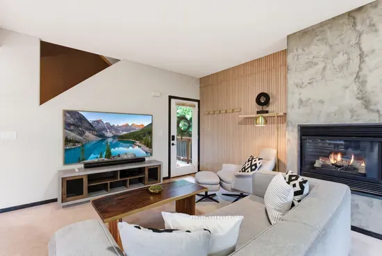 Modern cozy living room with fireplace, large TV, and stylish seating