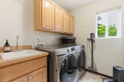 Bright laundry room with washer/dryer, utility sink, and ample storage