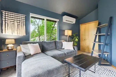 Cozy modern lounge with large sectional, leafy views, and stylish decor