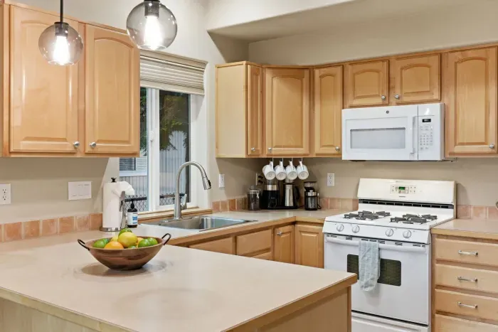 Bright kitchen with island, gas stove, and warm wood cabinetry