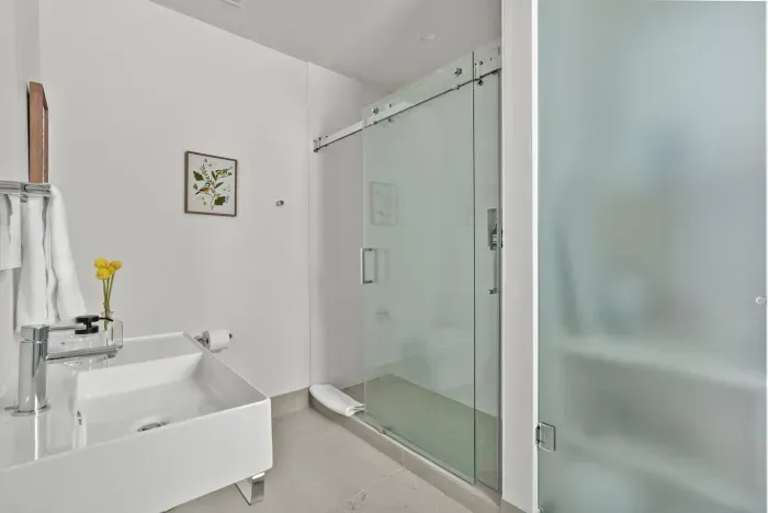 Luxurious and spacious full bathroom with walk in shower, toilet, sink, mirror, and laundry area. Soaps and towels provided.