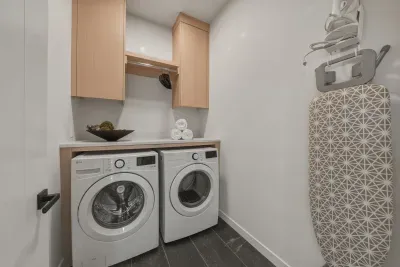 Modern in-home laundry room with washer, dryer, storage, and ironing board