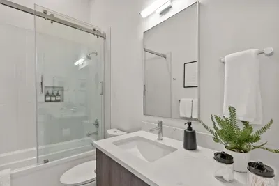 Bright modern bathroom with glass shower-tub combo and sleek vanity