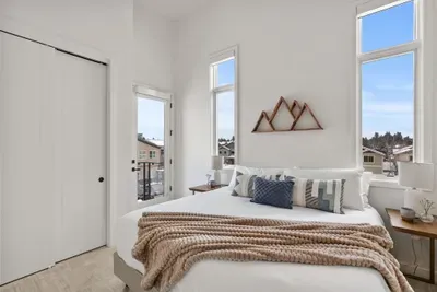 Bright, airy bedroom with soaring ceilings, tall windows, and cozy modern styling