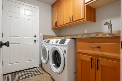 Laundry room with front-load washer and dryer, free for guest use. There is a utility sink nearby and laundry detergent for guest use.