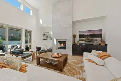 The living room is large with soaring ceilings, gas insert fireplace, smart TV with access to your apps, games, books, game console, free internet, a large sectional sofa with stylish chairs, coffee table, and open to the dining and kitchen areas