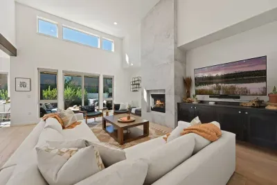 The living room is large with soaring ceilings, gas insert fireplace, smart TV with access to your apps, games, books, game console, free internet, a large sectional sofa with stylish chairs, coffee table, and open to the dining and kitchen areas