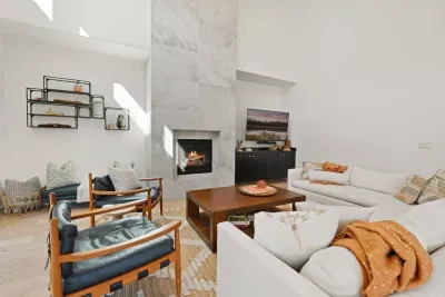 The living room is large with soaring ceilings, gas insert fireplace, smart TV with access to your apps, games, books, game console, free internet, a large sectional sofa with stylish chairs, coffee table, and open to the dining and kitchen areas