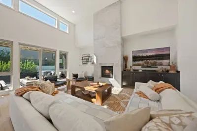 The living room is large with soaring ceilings, gas insert fireplace, smart TV with access to your apps, games, books, game console, free internet, a large sectional sofa with stylish chairs, coffee table, and open to the dining and kitchen areas