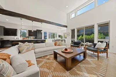 The living room is large with soaring ceilings, gas insert fireplace, smart TV with access to your apps, games, books, game console, free internet, a large sectional sofa with stylish chairs, coffee table, and open to the dining and kitchen areas