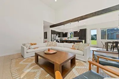 The living room is large with soaring ceilings, gas insert fireplace, smart TV with access to your apps, games, books, game console, free internet, a large sectional sofa with stylish chairs, coffee table, and open to the dining and kitchen areas