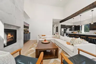 The living room is large with soaring ceilings, gas insert fireplace, smart TV with access to your apps, games, books, game console, free internet, a large sectional sofa with stylish chairs, coffee table, and open to the dining and kitchen areas