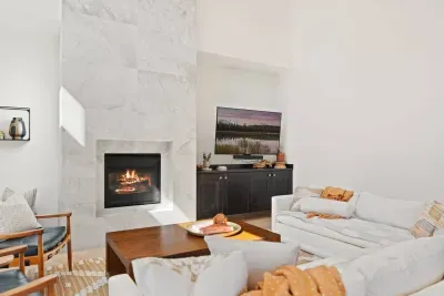 The living room is large with soaring ceilings, gas insert fireplace, smart TV with access to your apps, games, books, game console, free internet, a large sectional sofa with stylish chairs, coffee table, and open to the dining and kitchen areas