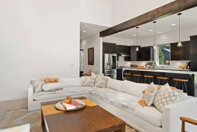 The living room is large with soaring ceilings, gas insert fireplace, smart TV with access to your apps, games, books, game console, free internet, a large sectional sofa with stylish chairs, coffee table, and open to the dining and kitchen areas