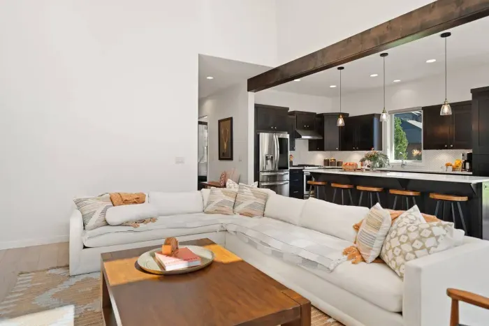 The living room is large with soaring ceilings, gas insert fireplace, smart TV with access to your apps, games, books, game console, free internet, a large sectional sofa with stylish chairs, coffee table, and open to the dining and kitchen areas