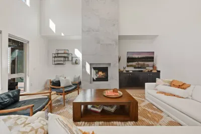 The living room is large with soaring ceilings, gas insert fireplace, smart TV with access to your apps, games, books, game console, free internet, a large sectional sofa with stylish chairs, coffee table, and open to the dining and kitchen areas