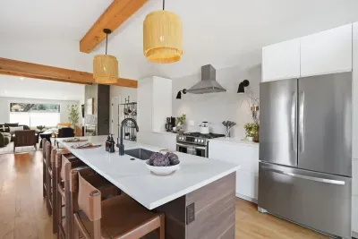 Sleek open kitchen with island seating, beams, and stainless appliances