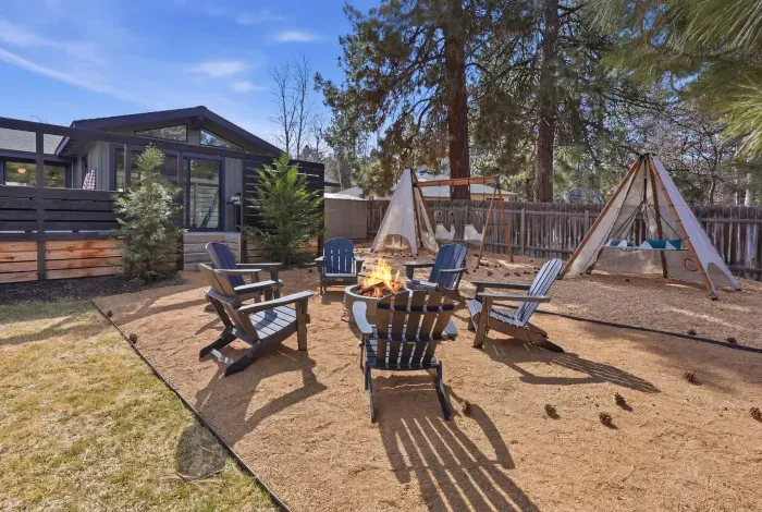 Backyard oasis with fire pit, Adirondack seating, teepees & swing set.