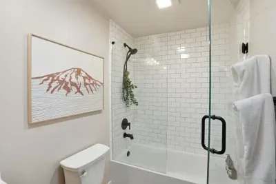 Bright bath with subway tile, glass tub/shower & matte-black fixtures