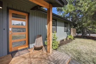 Modern covered porch with glass-panel door and landscaped yard