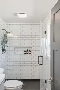 Sleek subway-tile shower with glass door, natural light, and luxe essentials