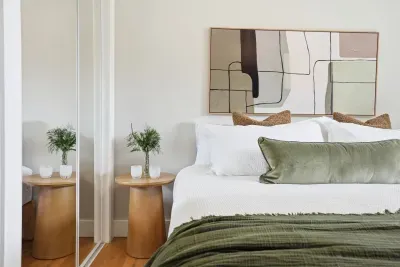 Serene bedroom with plush linens, artful decor & mirrored closet