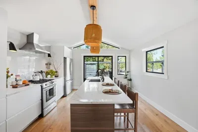 Bright chef’s kitchen with quartz island, vaulted ceiling, patio views