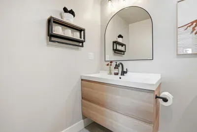 Sleek bath with floating vanity, arched mirror & black accents