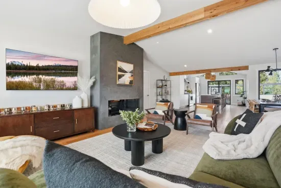 Airy living room with fireplace, beams, and open flow to kitchen/dining.