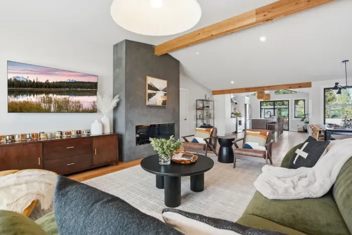 Airy living room with fireplace, beams, and open flow to kitchen/dining.