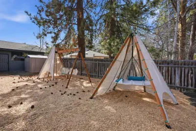 Fenced yard with teepee hammock swings—relax under the pines