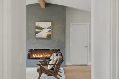 Cozy lounge with linear fireplace, vaulted beam ceiling, chic seating