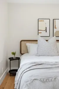 Serene bedroom with cane headboard, plush linens & modern art