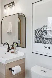 Modern bath with black fixtures, floating vanity, stylish Bend art.