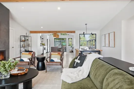Bright open-plan living with fireplace, island kitchen, and dining patio view.