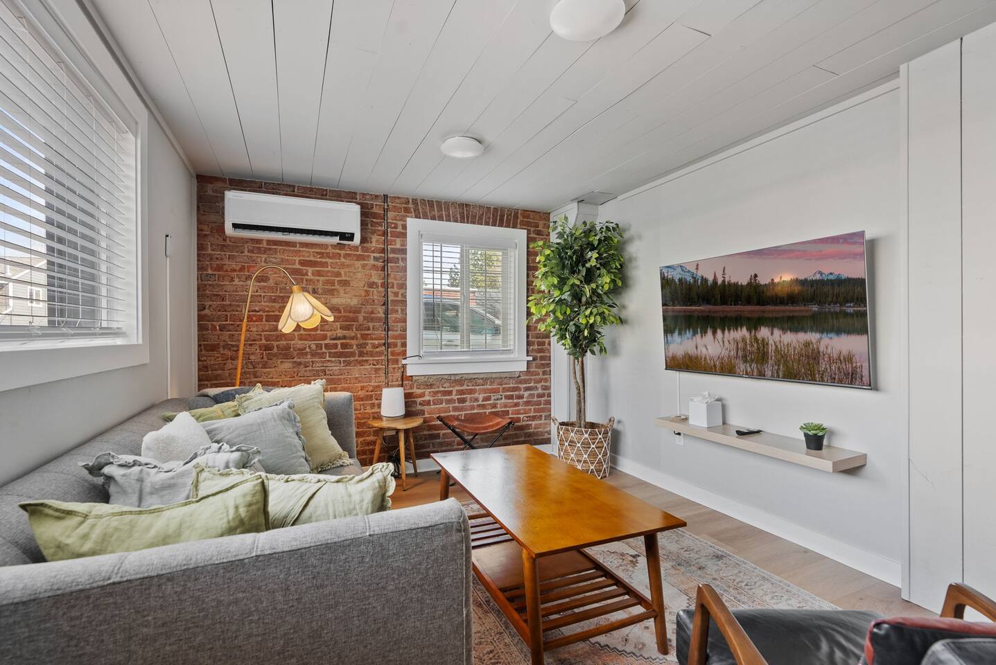 Cozy brick-accent living room with TV, natural light, and stylish decor